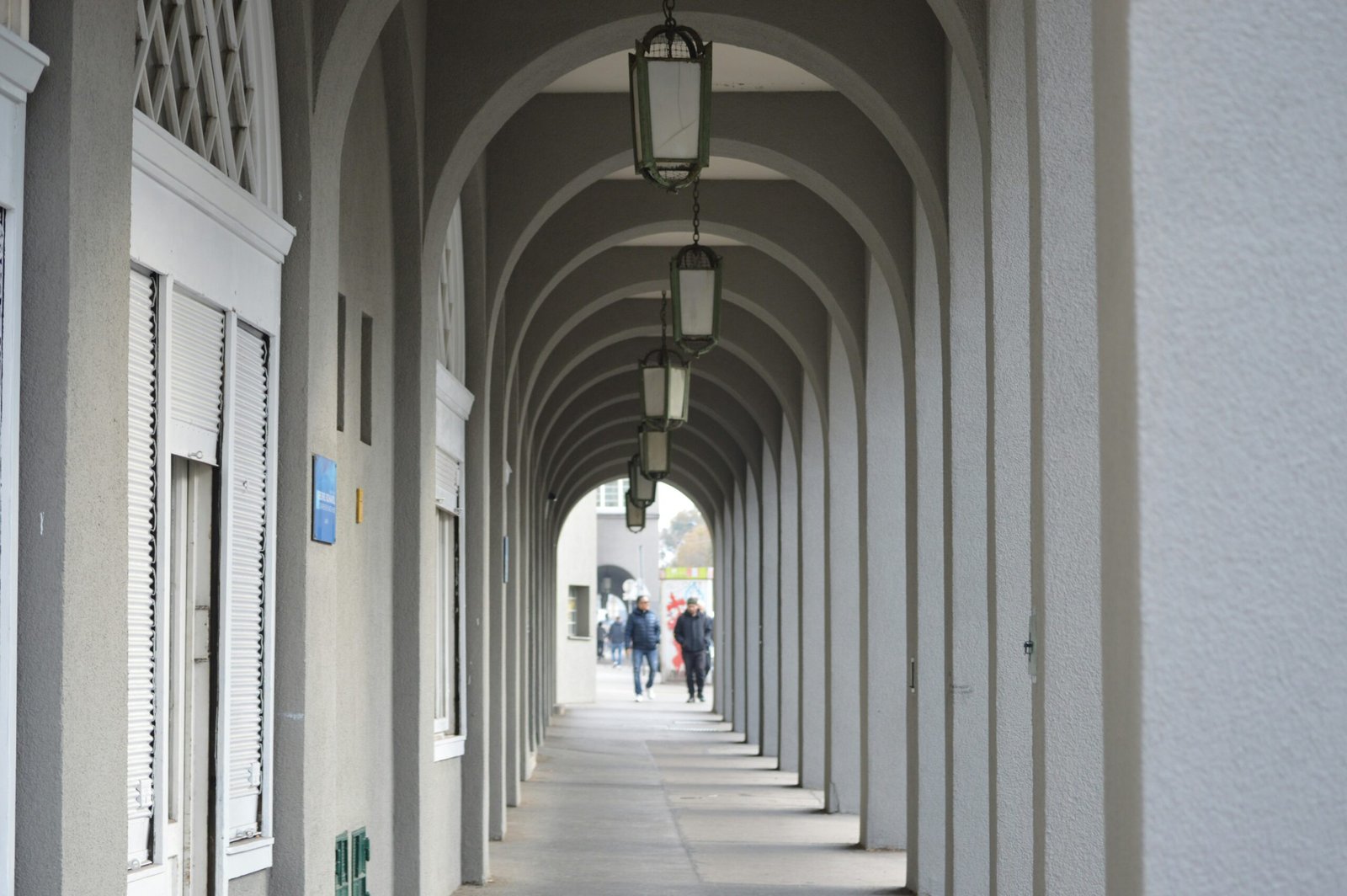 A row of white pillars with people walking down one of them